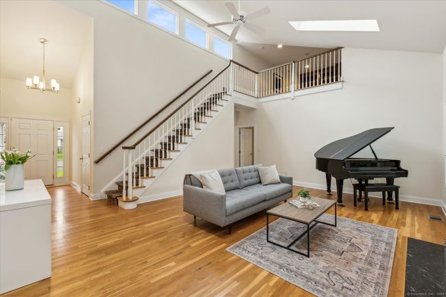 Tons of natural light flood the living room with hardwood floors and skylights. Stairs lead to the loft. | Image 15