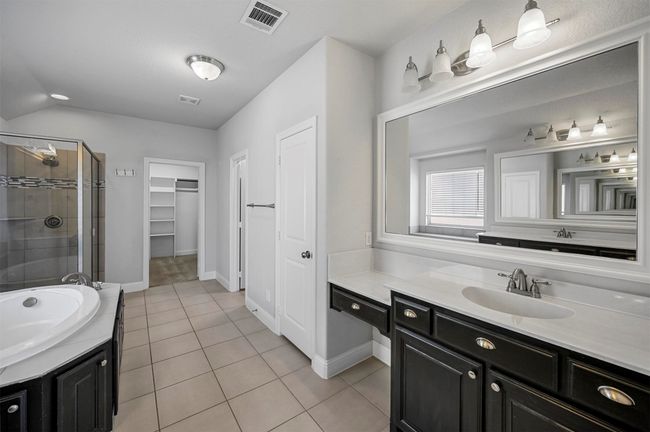 Full bath featuring visible vents, a walk in closet, a shower stall, tile patterned flooring, and vanity | Image 28