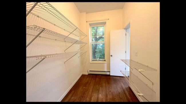 Spacious closet with wood finished floors and baseboard heating | Image 16