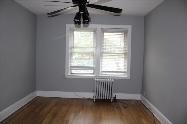 Empty room featuring radiator, ceiling fan, wood finished floors, and baseboards | Image 13
