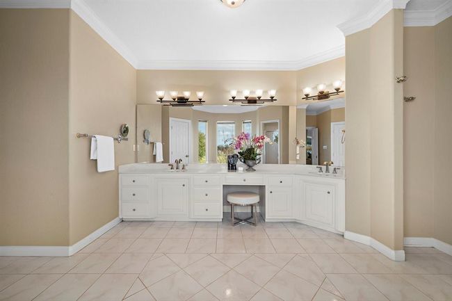 The vanity area with generous storage and integrated seating elevates the bathroom's luxury and functionality. | Image 26