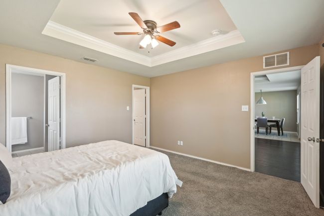 Bedroom featuring ornamental molding, visible vents, and a raised ceiling | Image 23