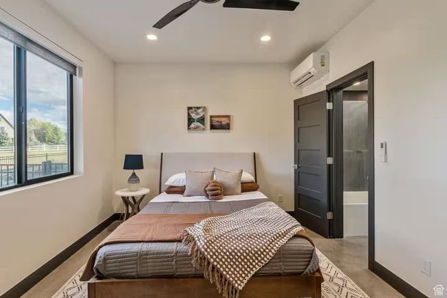 Bedroom with recessed lighting, ceiling fan, a wall mounted air conditioner, concrete floors, and baseboards | Image 56