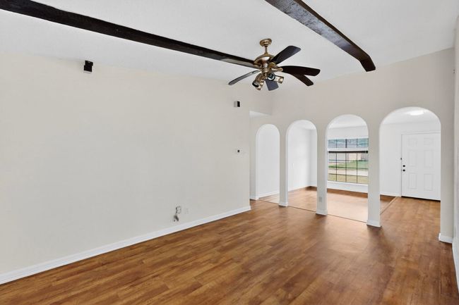 Spare room featuring beamed ceiling, a ceiling fan, arched walkways, and wood finished floors | Image 7
