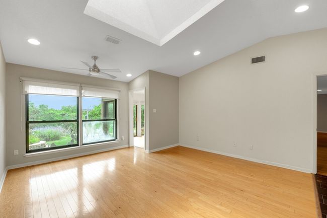 Unfurnished living room featuring ceiling fan, visible vents, light wood-style flooring, baseboards, and lofted ceiling | Image 11