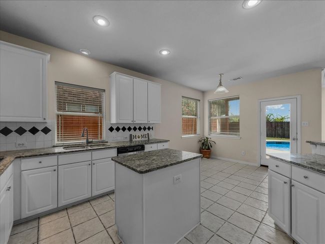 Kitchen with light tile patterned floors, white cabinetry, a kitchen island, recessed lighting, and decorative backsplash | Image 8