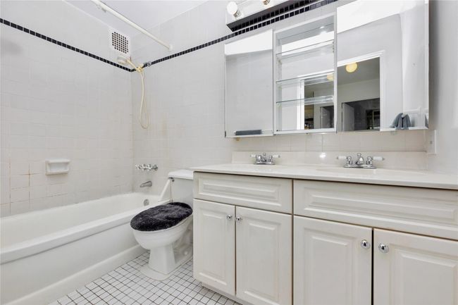 Bathroom with double vanity, shower / washtub combination, tile patterned floors, and backsplash | Image 9