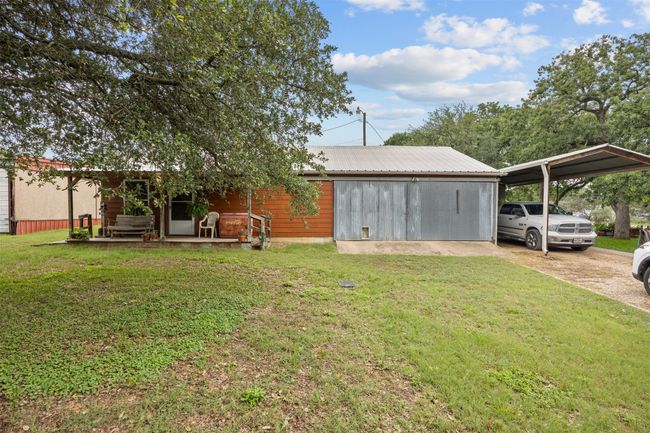 View of front of cabin, featuring a detached garage and carport, all with metal roofs | Image 25