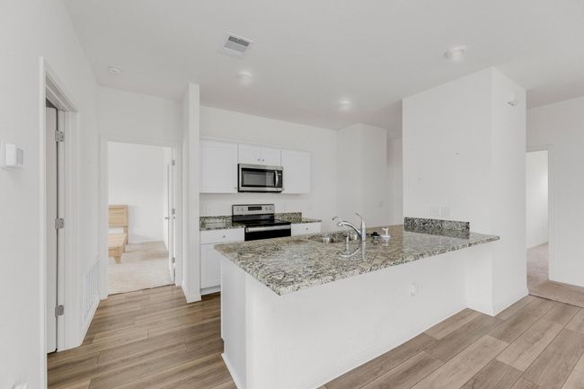 The stylish kitchen is equipped with modern granite countertops and sleek stainless-steel appliances. | Image 10