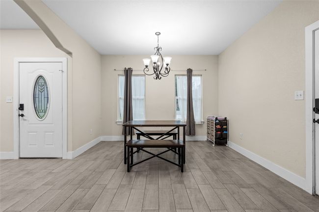 Dining space featuring a chandelier, light wood-style flooring, and arched walkways | Image 16