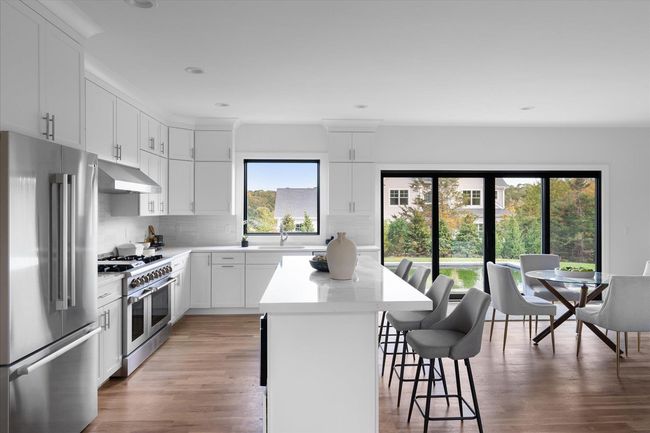 Kitchen featuring a kitchen bar, sink, a center island, premium appliances, and white cabinets | Image 7