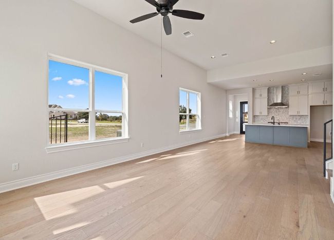 Unfurnished living room featuring a wealth of natural light, visible vents, light wood-type flooring, and a ceiling fan | Image 10