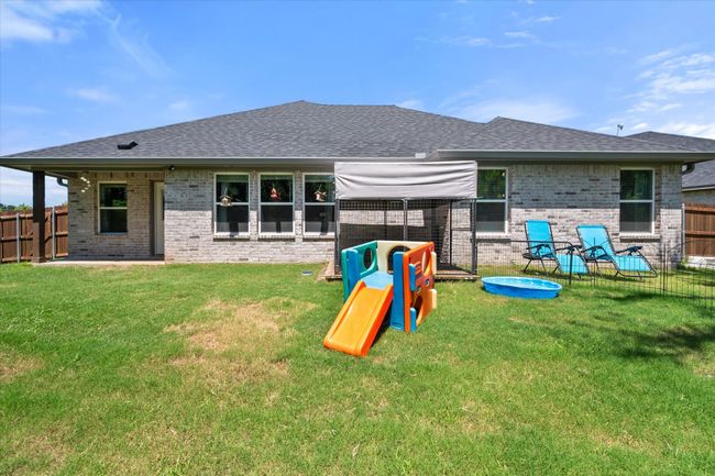 Back of house featuring a fenced backyard, brick siding, and roof with shingles | Image 23