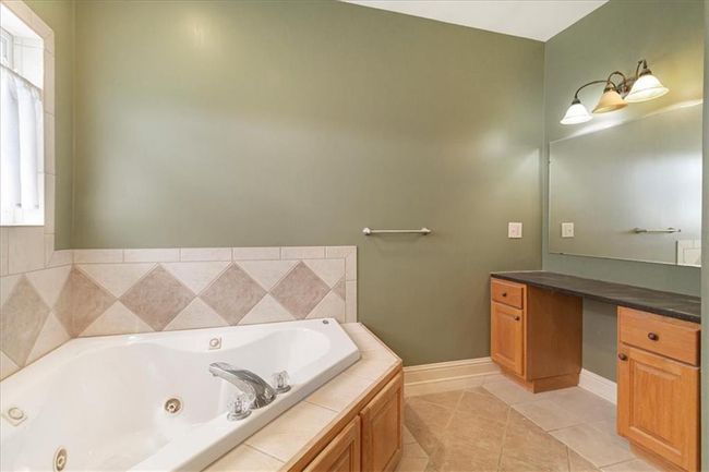Full bathroom with a whirlpool tub, baseboards, tile patterned flooring, and vanity | Image 29