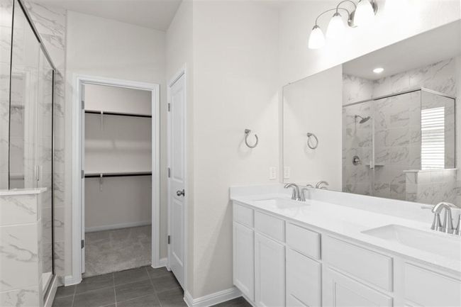 Bathroom featuring double vanity, a spacious closet, a sink, and a marble finish shower | Image 23