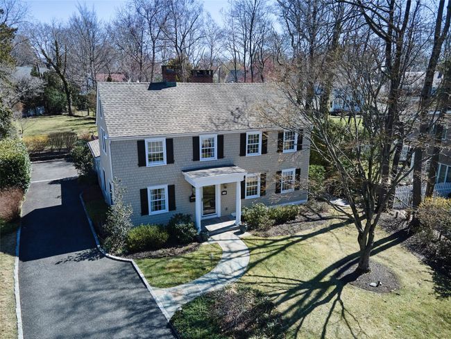 Colonial inspired home with driveway, a chimney, a front lawn, and roof with shingles | Image 33
