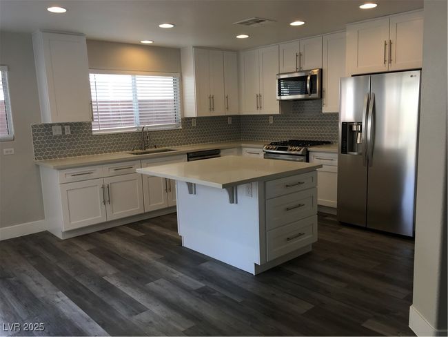 Kitchen featuring white cabinets, a sink, visible vents, stove, and refrigerator | Image 6