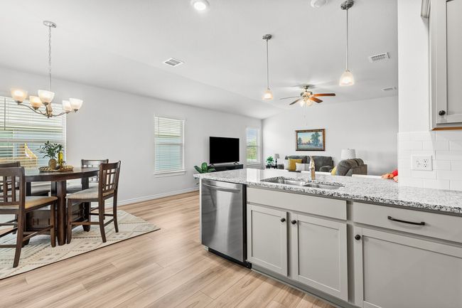 Kitchen with dishwasher, light wood finished floors, open floor plan, a chandelier, and tasteful backsplash | Image 19