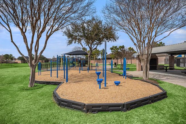 The space features a modern playground setup with blue climbing structures, slides, and activity stations surrounded by mulch for safety. | Image 31