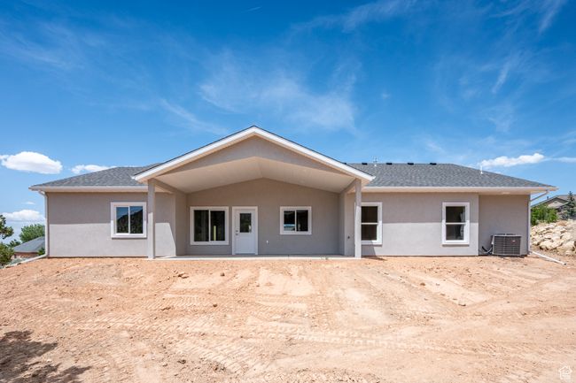 Rear view of property featuring stucco siding, central AC unit, and a shingled roof | Image 50