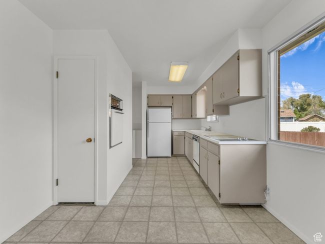 Kitchen with light countertops, a sink, baseboards, and white appliances | Image 8