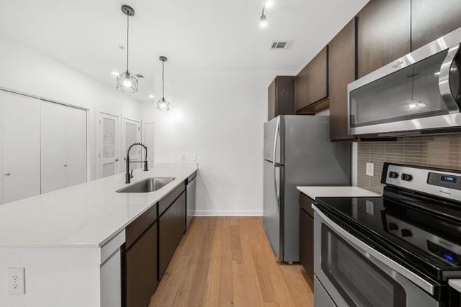 Kitchen with visible vents, a sink, tasteful backsplash, stainless steel appliances, and a peninsula | Image 6