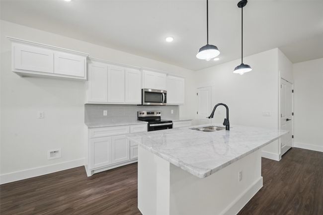 Kitchen with backsplash, a sink, dark wood-style floors, stainless steel appliances, and white cabinets | Image 8