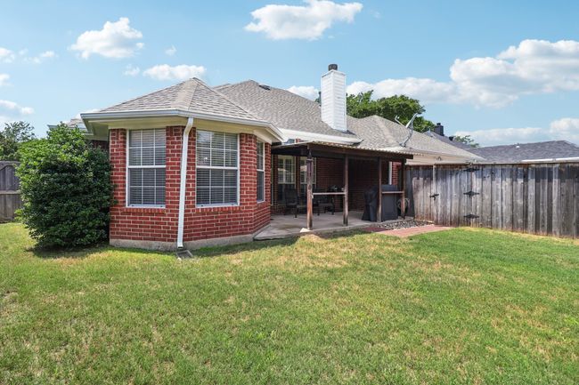 Rear view of property with brick siding, a patio area, a chimney, and a shingled roof | Image 37