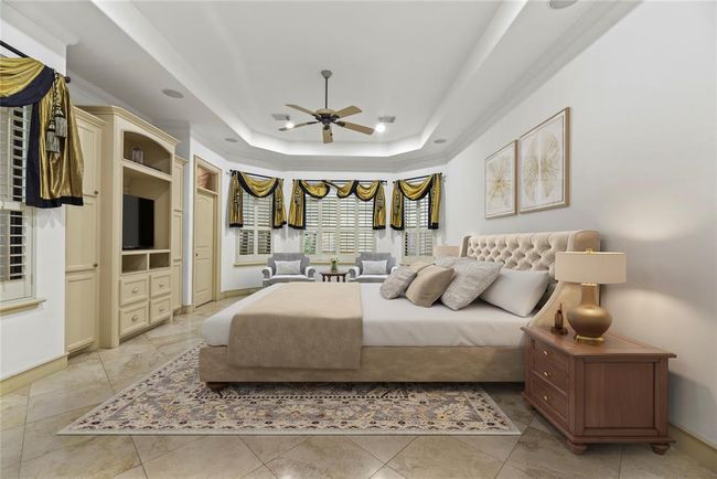 Primary Bedroom features tile floors, built-ins, tray ceiling, plantation shutters & a spa like ensuite. | Image 15