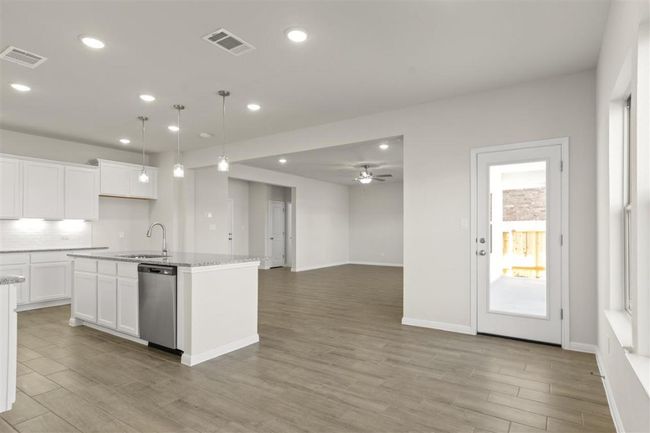 Kitchen with light wood-style flooring, a kitchen island with sink, visible vents, stainless steel dishwasher, and a sink | Image 10