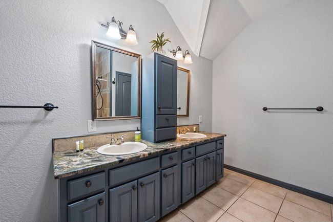 Full bathroom with double vanity, tile patterned flooring, a sink, and lofted ceiling | Image 23