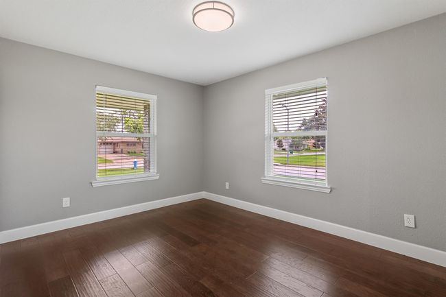 Secondary bedroom has engineered wood floors and picture windows. | Image 21