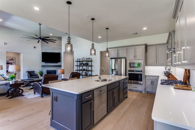 Kitchen featuring stainless steel appliances, light wood-style flooring, open floor plan, light countertops, and gray cabinetry | Image 16