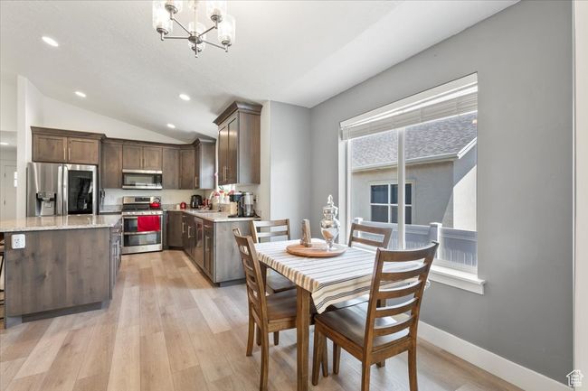 Dining space featuring light wood-style floors, vaulted ceiling, a chandelier, recessed lighting, and baseboards | Image 12