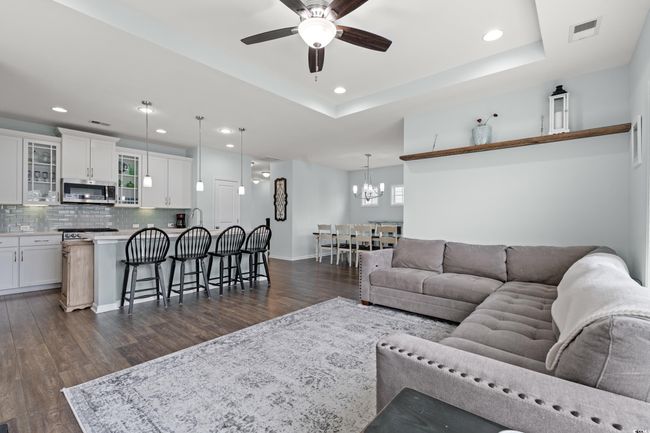 Open Concept living area on the second level featuring recessed lighting, a tray ceiling, ceiling fan, large gas fireplace and large windows with a pond view. | Image 24