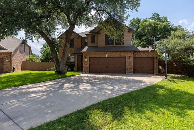 Traditional-style home featuring concrete driveway, an attached garage, brick siding, and roof with shingles | Image 37