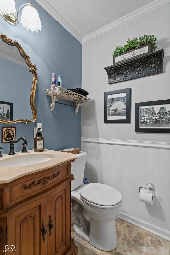 half bath on the main level featuring crown molding, a textured ceiling, toilet, and vanity | Image 17