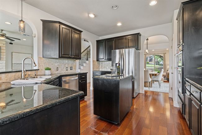 Kitchen with pendant lighting, arched walkways, dark brown cabinetry, dark wood-style floors, and stainless steel appliances | Image 17