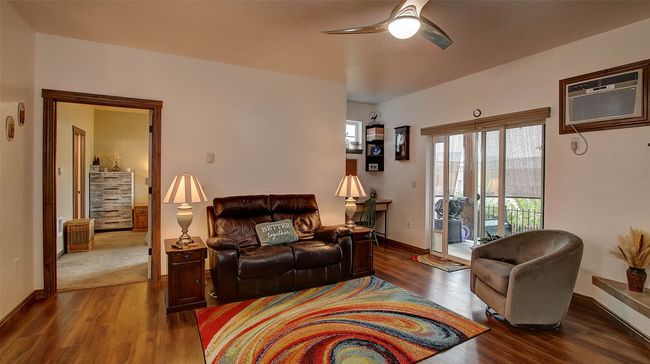 Spacious Living Room featuring LVP flooring, gas fireplace, tv wall mount, sliding door to patio, overhead ceiling fan, access to primary suite. | Image 6