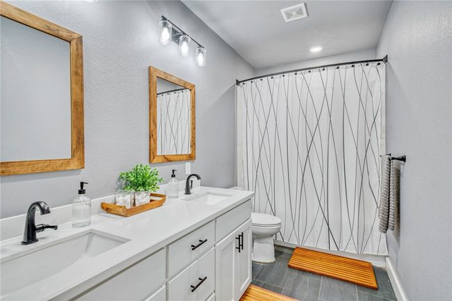 Bathroom featuring a shower with curtain, vanity, and toilet | Image 29