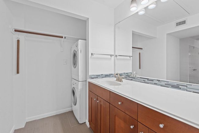 Washroom featuring stacked washer / dryer, baseboards, visible vents, and a sink | Image 29