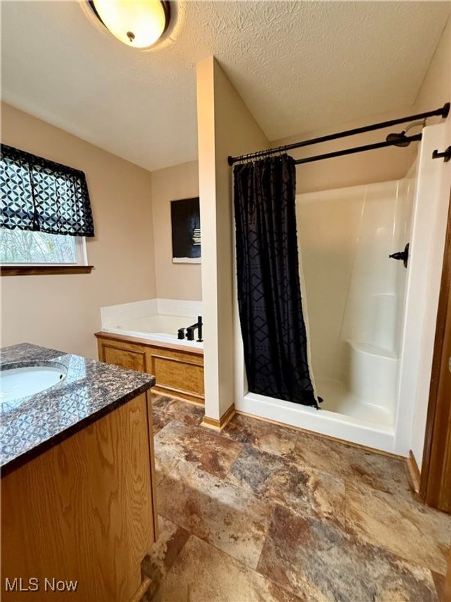 Bathroom with a shower stall, vanity, stone finish flooring, a bath, and baseboards | Image 19