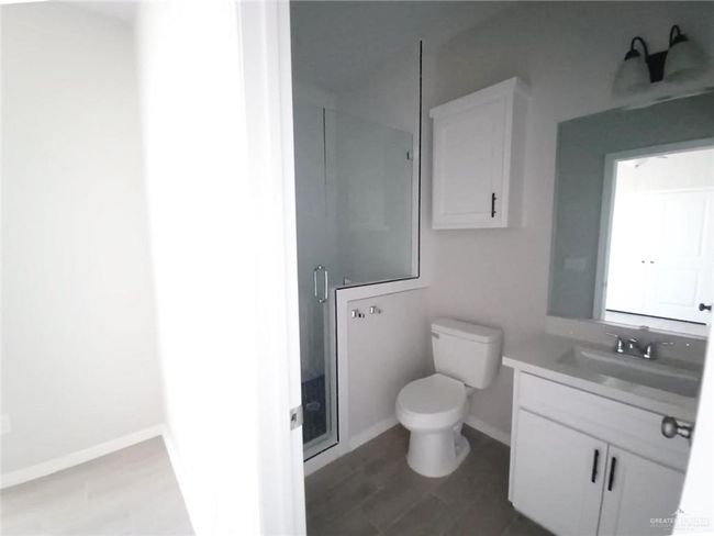 Bathroom featuring vanity, toilet, a shower stall, baseboards, and wood finished floors | Image 11