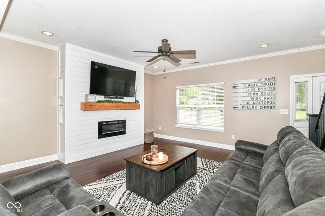 living area with a ceiling fan, baseboards, wood finished floors, a fireplace, and recessed lighting | Image 7