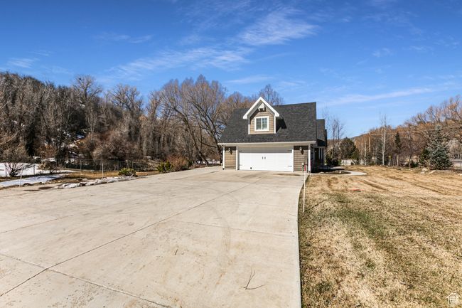 View of property exterior with driveway, a garage, a lawn, and fence | Image 52