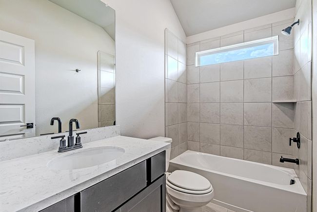 Upstairs bathroom with soft neutral tile, quartz countertops, and stylish black hardware—perfectly placed between secondary bedrooms. | Image 37