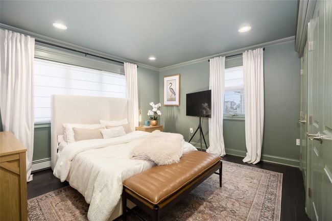Bedroom featuring multiple windows, baseboard heating, dark wood-style flooring, and crown molding | Image 26