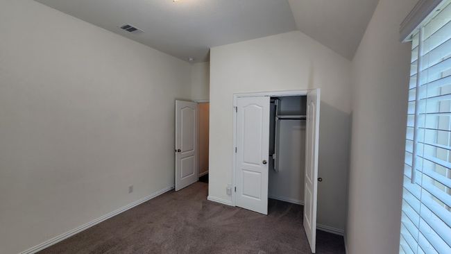 Unfurnished bedroom featuring carpet, vaulted ceiling, a closet, and baseboards | Image 18