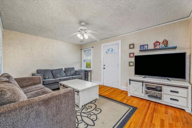 Unit # 70 Living room featuring ceiling fan, a textured ceiling, and hardwood / wood-style flooring | Image 25