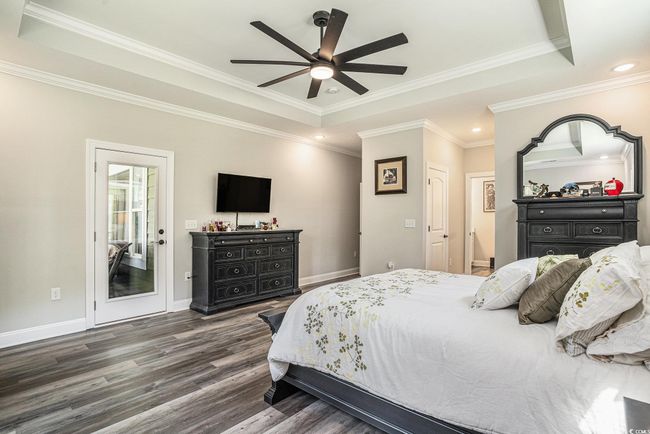 Bedroom with a raised ceiling, wood finished floors, crown molding, baseboards, and recessed lighting | Image 24